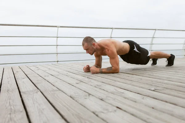 Çıplak Gövdeli Yakışıklı Adam Sahilde Kalas Egzersizi Yapıyor — Stok fotoğraf
