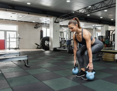 Spor giyim mağazasındaki genç kaslı kadın spor salonunda su ısıtıcısı ile asansör kaldırıyor. Sağlıklı yaşam tarzı kavramı. Fonksiyonel eğitim