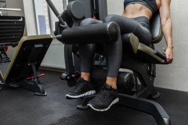 Bacak egzersizi. Spor salonundaki egzersiz makinesinde bacak uzatmak isteyen genç bir kadın..