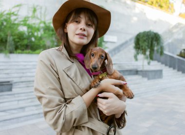 Genç bir moda kadınının portresi ve şehir parkındaki sevimli bir köpek yavrusu. Sahibe ve evcil hayvan