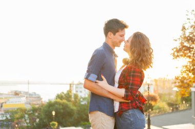 Birbirine aşık genç bir çift. Güler yüzlü kız ve erkek arkadaşı şehirde gün doğumunda sarılıyorlar.