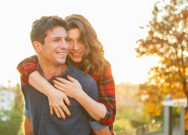 Birbirine aşık genç bir çift. Güler yüzlü kız ve erkek arkadaşı şehirde gün doğumunda sarılıyorlar.