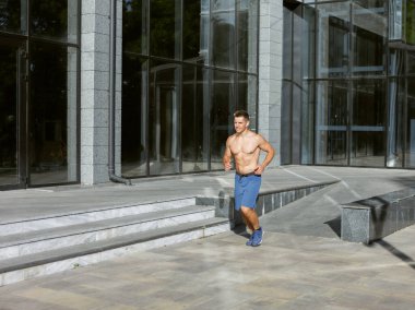 Genç atletik koşucu dışarıda koşuyor. Kardiyo çalışması, sağlıklı yaşam tarzı.