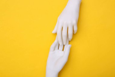 Mankenin beyaz elleri sarı arka planda birbirine dokunur. Minimalizm. Sanat kavramı