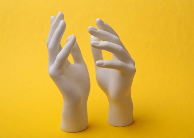 Beyaz El mankeni sarı arka planda duruyor. Minimalizm. Yaratıcı sanat