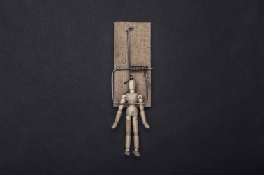 Siyah arka planda fare kapanına yakalanmış tahta bir kukla.