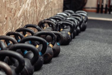 Spor salonunda yerde bir sıra kettlebell.