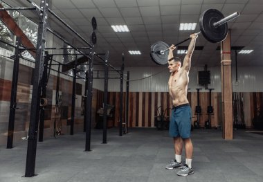 Modern sağlık kulübünde kaslı bir adam ağır halter çalışıyor. Vücut geliştirme ve Fitness