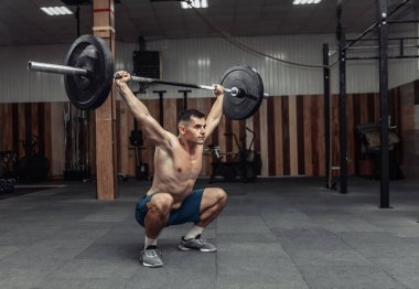 Modern sağlık kulübünde kaslı bir adam ağır halter çalışıyor. Vücut geliştirme ve Fitness
