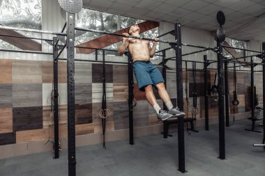 Modern sağlık kulübünün yatay çubuğunda egzersiz yapan kaslı erkek sporcu. Barfiks