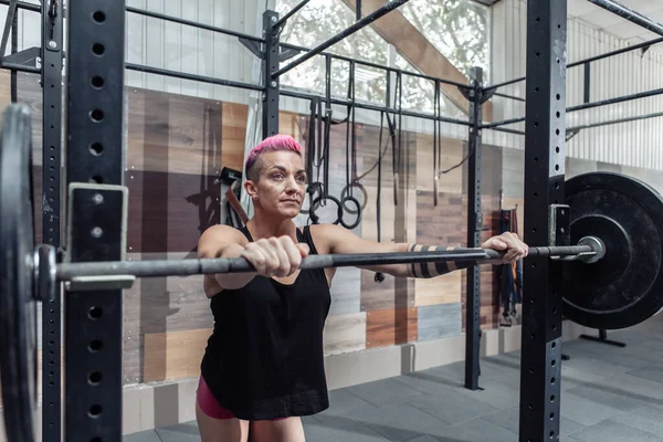 Spor salonunda halterine yaslanmış yorgun bir kadın sporcu. Vücut geliştirme ve spor. Fonksiyonel eğitim