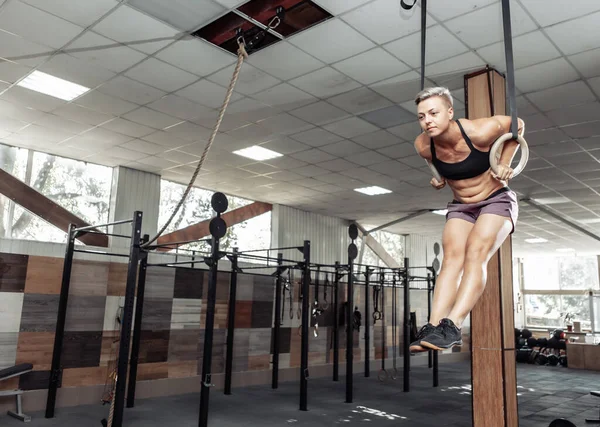 athletic sport woman exercising with gymnastics rings in modern cross gym