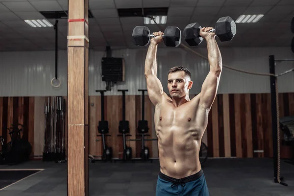 Spor salonunda omuzlarında ağır dambıllarla omuz kaslarını çalıştıran güçlü bir atletik. Sağlıklı yaşam tarzı kavramı