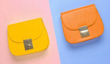Pastel renkli arka planda turuncu ve sarı deri mini çantalar. Minimalizm moda kavramı. Üst görünüm