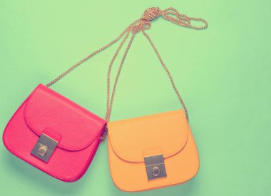 Kırmızı ve sarı, sarı zincire bağlı iki deri çanta. Minimalizm moda kavramı. Üst görünüm