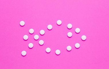 Pembe arka planda beyaz haplardan oluşan bir balık türü. Tıbbi minimalist konsept, üst görünüm