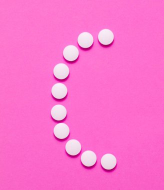 C vitamini. Pembe arka planda beyaz haplardan. Asgari tıbbi konsept. Üst görünüm.