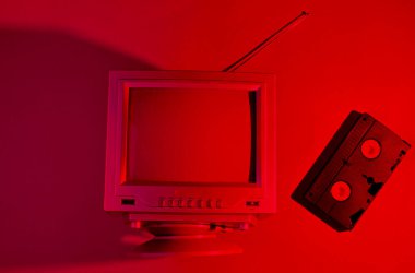 Retro dalga, minimalizm 80 'ler konsepti. Antenli Retro TV, video kaset. Neon kırmızı ışık. Üst görünüm