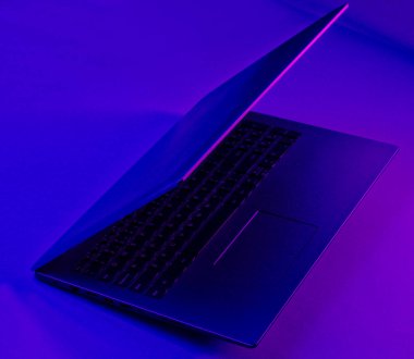 Canlı menekşe mavisi neon ışıklı modern dizüstü bilgisayar. Ofis sürrealizmi konsepti.