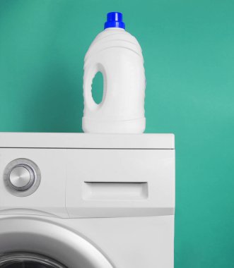 Çamaşır makinesinde mavi arka planda bir şişe çamaşır jeli.