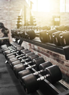 Spor salonundaki askıda metal saplı siyah halterler. Serbest ağırlık çalışması, vücut geliştirme.