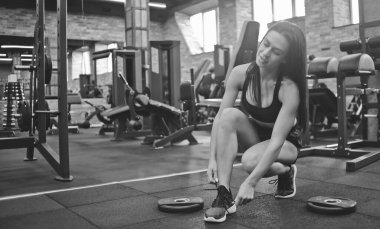 Çekici esmer kadın spor salonunda ayakkabılarını bağlıyor..