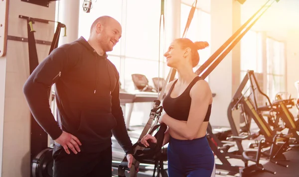 Happy fit woman and man talking during a break from exercise with fitness straps