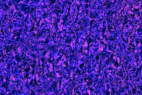 Texture of crumpled foil with a holographic blue-purple glow