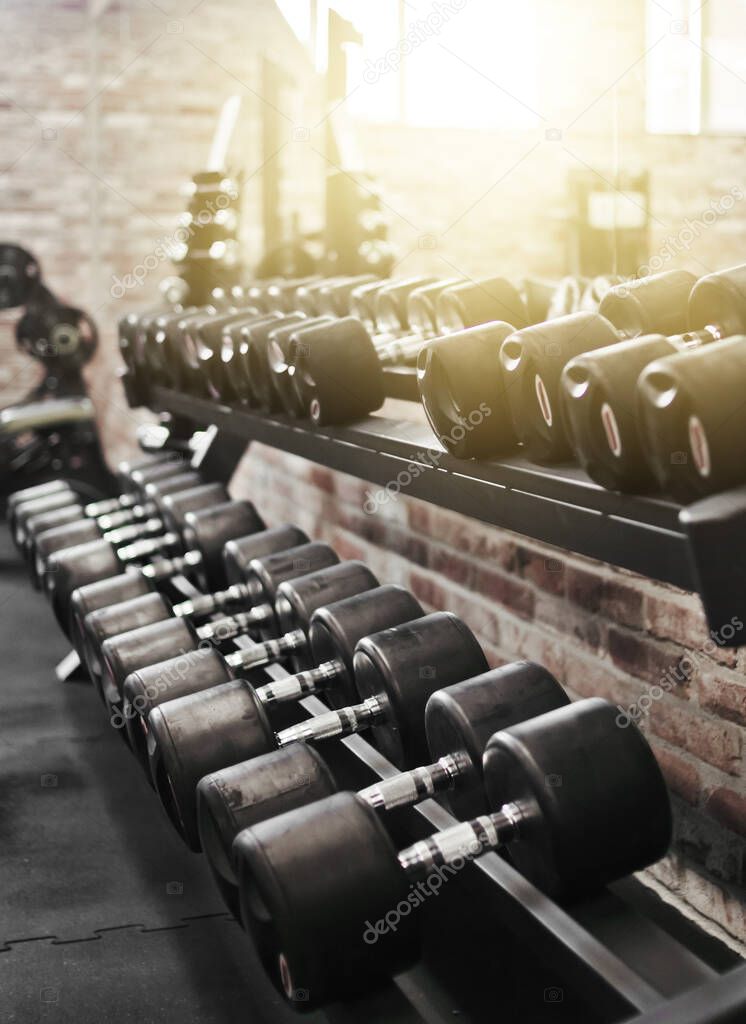Set of black dumbbell with metal handles on a rack in the gym. Free weights training, bodybuilding