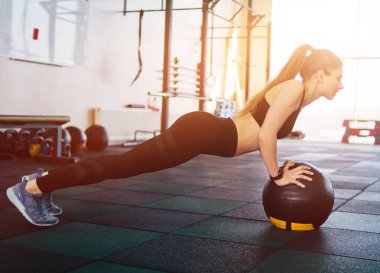 Atletik çekici bir kadın, spor yaparken ilaç topuyla şınav çekiyor. Fonksiyonel eğitim