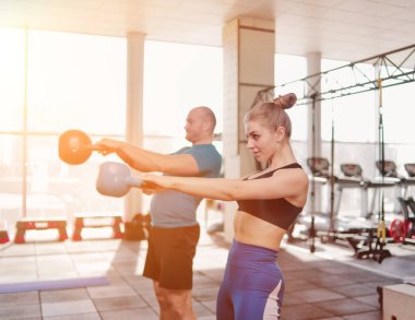 çift fonksiyonel eğitim. Sportif erkek ve formda kadın spor salonunda kettlebell ile egzersiz yapıyor.