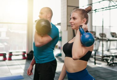 çift fonksiyonel eğitim. Sportif erkek ve formda kadın spor salonunda kettlebell ile egzersiz yapıyor.
