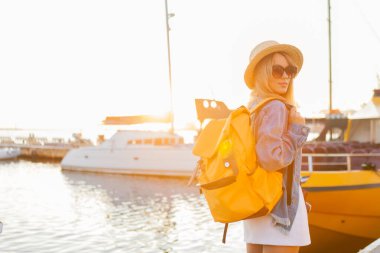 Gündoğumunda denizde büyük bir sırt çantasıyla gezen genç bir turist. Seyahat ve turizm kavramı