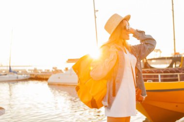 Gündoğumunda denizde büyük bir sırt çantasıyla gezen genç bir turist. Seyahat ve turizm kavramı