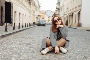 Genç, neşeli, güzel bir kadın Avrupa 'da bir caddenin ortasında oturuyor..