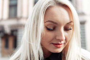 Şehirde renkli kirpikleri olan çekici sarışın kadın portresi.