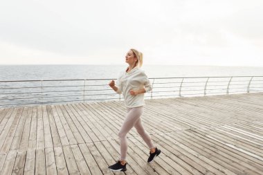 Spor giyimli genç bayan koşucu sahilde koşuya hazırlanıyor. Kardiyo çalışması