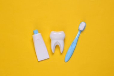 Sahte diş fırçası, diş fırçası ve sarı arka planda diş macunu. Üst görünüm