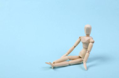 Ahşap kukla mavi arka planda tek başına oturur.