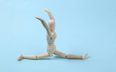 Ahşap kukla mavi arka planda sicimde oturuyor.