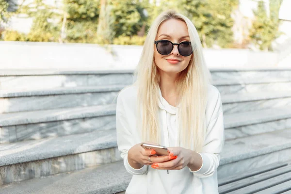 Ung Attraktiv Blond Kvinna Solglasögon Med Smartphone När Sitter Bänk — Stockfoto