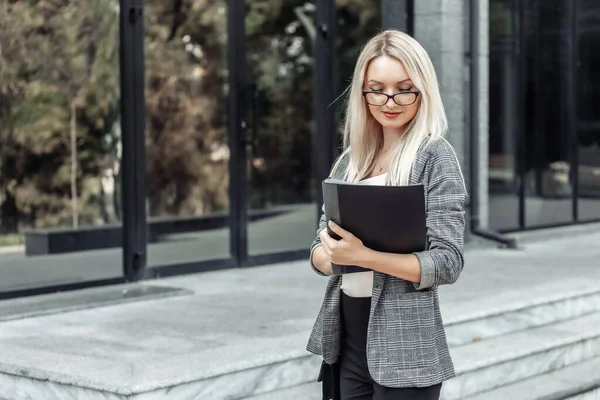 busy blonde business woman with folder at office building