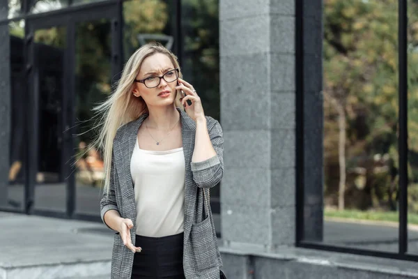 Seriöse Junge Attraktive Geschäftsfrau Telefoniert Vor Dem Hintergrund Einer Geschäftsstelle — Stockfoto