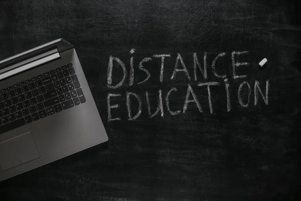 Distance education words chalk hand drawn on blackboard and laptop. Online learning