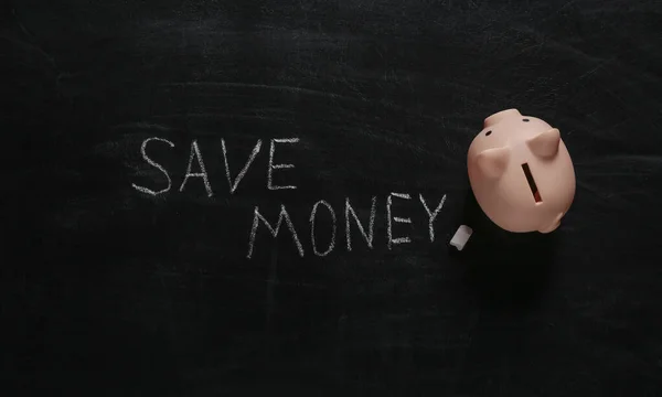 Word Save money hand drawn on blackboard and piggy bank