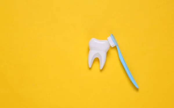 Szczoteczka Czyści Sztuczny Ząb Żółtym Tle Koncepcja Opieki Stomatologicznej — Zdjęcie stockowe