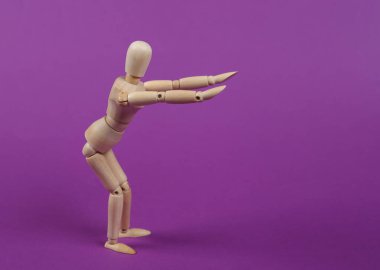 Ahşap kukla, mor arka plan üzerinde egzersiz yapıyor. Sağlıklı yaşam tarzı kavramı