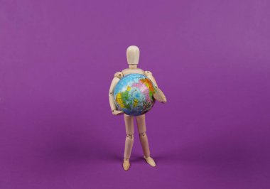 Yeryüzünü tutan tahta kukla mankeni mor arka planda taklit ediyor. Dünya Günü