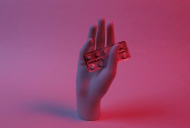 Manken elinde kırmızı-mavi neon ışıkta su toplayan haplar var. Minimalizm