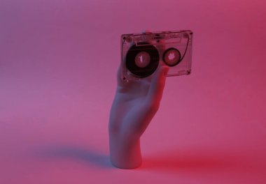 Manken elinde kırmızı-mavi neon ışıkta ses kaseti var. Minimalizm